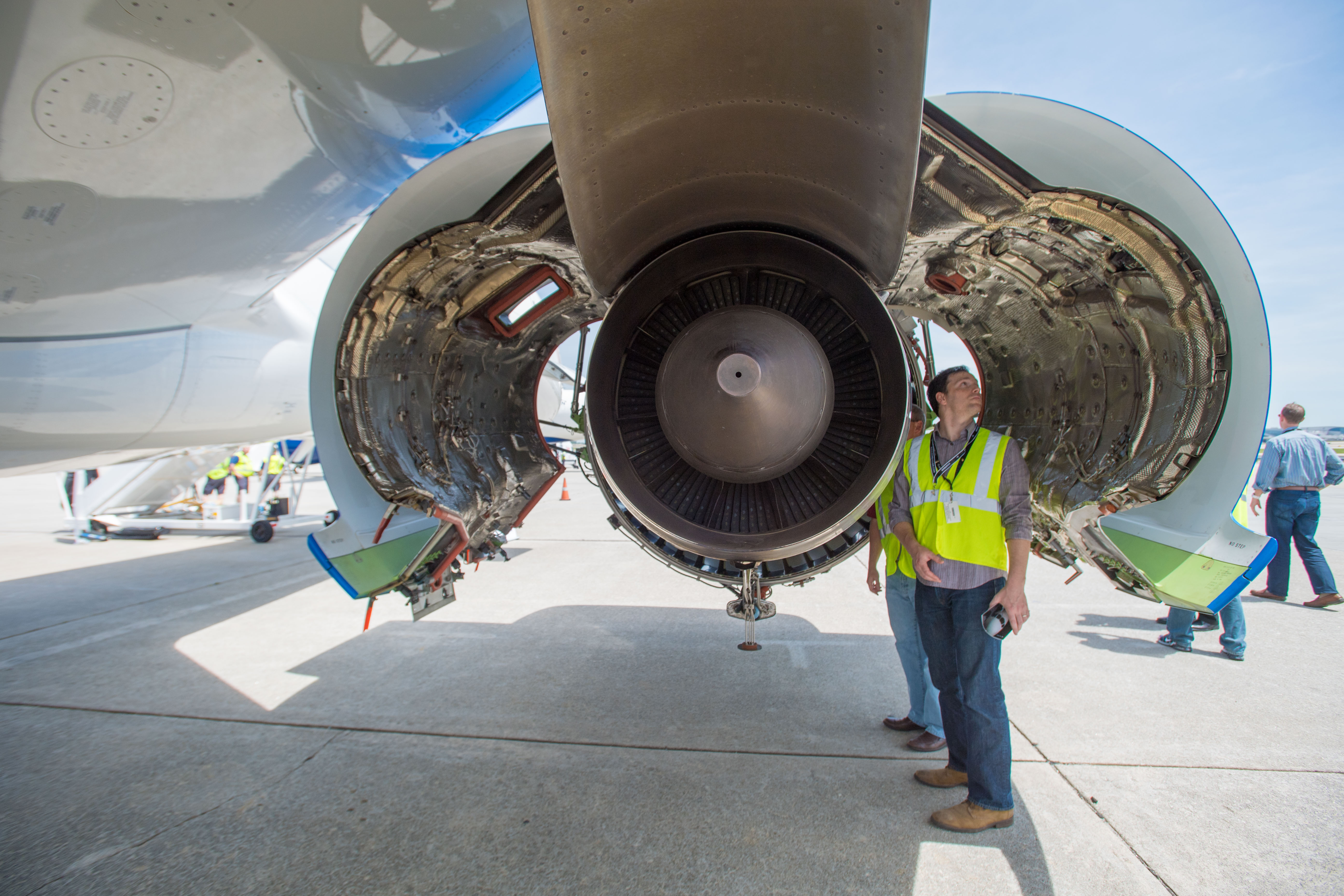 Underneath the wing of an Airbus A220 aircraft with cowlings open and a Pratt & Whitney PW1000G engine displayed