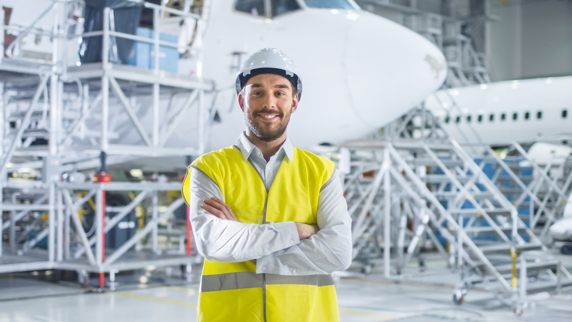 A maintenance technician stands next to multiple aircraft undergoing maintenance