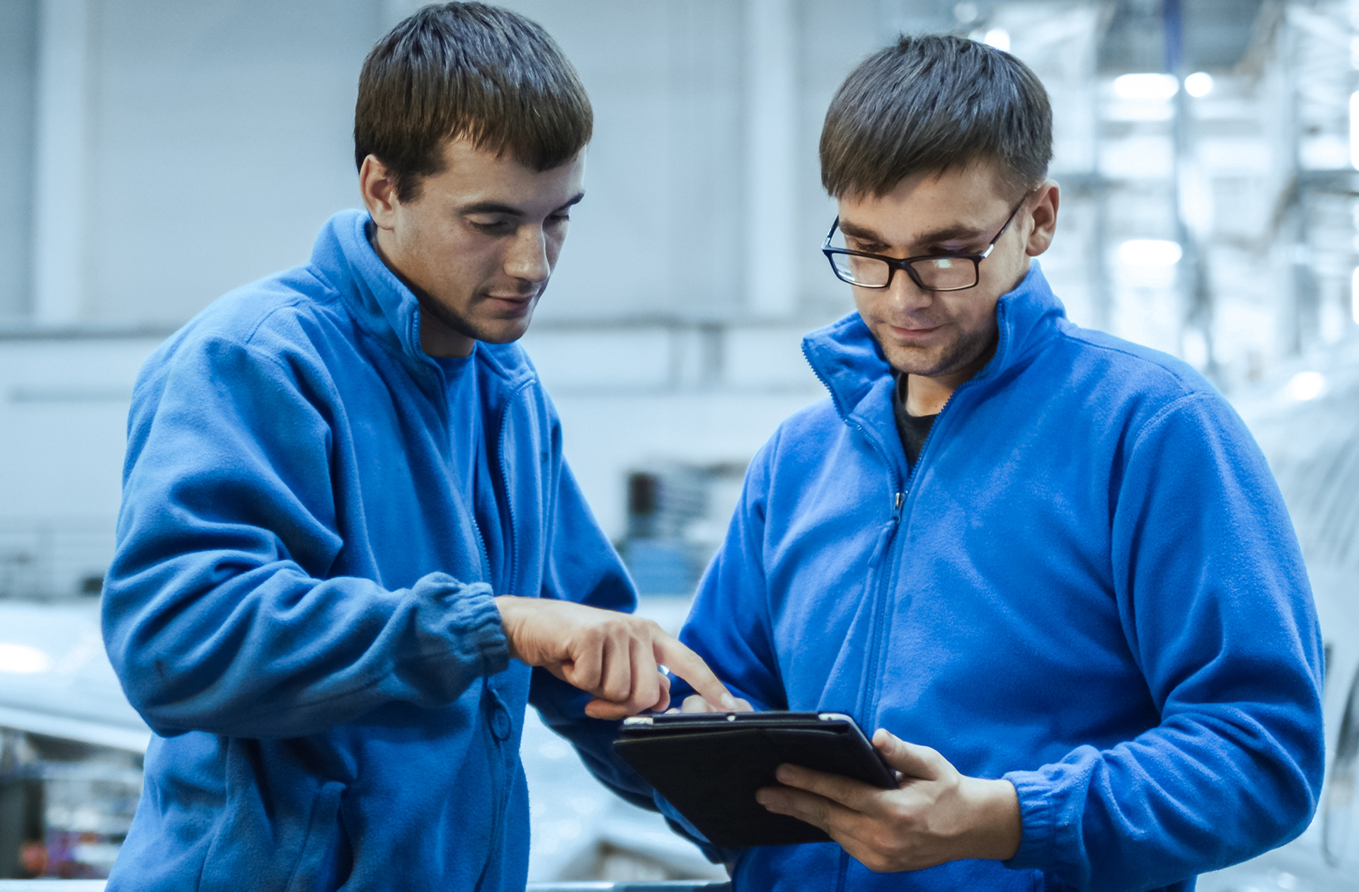 Two Aircraft Maintenance Engineers (AMEs) view a tablet in an aircraft hanager